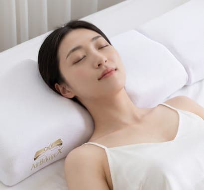 흰색 AirBridgeX 베개를 베고 편안한 표정으로 바로 누운 여성